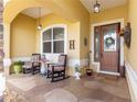Inviting front porch with rocking chairs, stone pillars, a decorative front door and patterned concrete at 13885 Del Webb Blvd, Summerfield, FL 34491