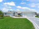 Inviting single-story home featuring a light blue exterior, lush green lawn and a spacious two-car garage at 17755 Se 117Th Cir, Summerfield, FL 34491