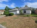 Side view of a single-story home with an attached two-car garage and simple landscaping at 17974 Se 115Th Cir, Summerfield, FL 34491