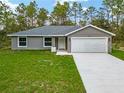 Charming single-story home features a well-manicured lawn, gray exterior, and attached garage for a welcoming curb appeal at 23163 Nw Shamrock Ave, Dunnellon, FL 34431