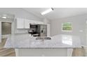 Well-lit kitchen with granite countertops, modern stainless steel appliances, and wood look floors at 24144 Nw Water Oak Ave, Dunnellon, FL 34431