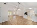 Bright, open-concept living room flowing into kitchen, featuring modern light fixtures and beautiful wood-look flooring at 4886 Nw 30Th Pl, Ocala, FL 34482