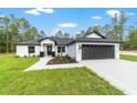 Eye-catching single-story home with a black two-car garage, white siding, and well-manicured lawn at 7483 Sw 121St Ter, Dunnellon, FL 34432
