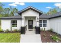 Inviting front porch features decorative columns, modern lighting, and a stylish front door at 7483 Sw 121St Ter, Dunnellon, FL 34432