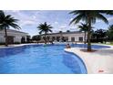 Large community pool with palm trees, lounge chairs, and inviting blue water at 8582 Pinecrest Trl, Wildwood, FL 34785