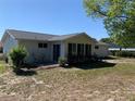 Rear view of a home with a patio, sunroom, and a partially shaded yard at 11445 Sw 84Th Avenue Rd, Ocala, FL 34481