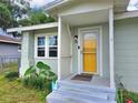 Inviting covered front porch with yellow door, providing a charming entrance to this home at 116 Nw 17Th Pl, Ocala, FL 34475