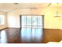 Living room featuring hardwood floors, vaulted ceilings, fan, and large sliding glass doors to the lanai at 1402 Arredondo Dr, The Villages, FL 32162