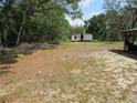 Exterior shot of a single-wide mobile home on a spacious lot with mature trees and partially cleared land at 1737 Griffin Ave, Lady Lake, FL 32159