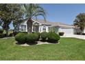 Inviting home featuring a well-kept lawn, lush greenery, and a decorative palm tree in a stone bed at 2550 Nw 55Th Avenue Rd, Ocala, FL 34482