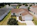 Aerial shot showcases this charming home with manicured landscaping and a convenient attached two-car garage at 2594 Berrington Loop, The Villages, FL 32162