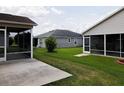 Exterior view of screened in back porches and an expanse of green grass in the backyard at 2594 Berrington Loop, The Villages, FL 32162