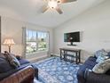 Cozy living room featuring a large window, comfortable seating, and ceiling fan for a welcoming ambiance at 32 Pine Course Loop, Ocala, FL 34472