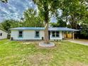 Charming single-story home with blue metal roof, white siding, and a mature tree in the front yard at 6134 Se Stetson Rd, Belleview, FL 34420
