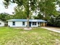 Charming single-story home with blue metal roof, white siding, and a mature tree in the front yard at 6134 Se Stetson Rd, Belleview, FL 34420