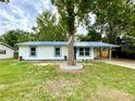 Charming single-story home with blue metal roof, white siding, and a mature tree in the front yard at 6134 Se Stetson Rd, Belleview, FL 34420