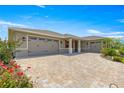 Spacious home with a three-car garage and a brick-paved driveway, enhanced by colorful flowerbeds at 8111 Sw 95Th Ct, Ocala, FL 34481