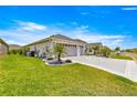 Well-maintained home with a lush green lawn, beautiful landscaping, and a wide driveway leading to a two-car garage at 907 Trifu Ter, The Villages, FL 32163