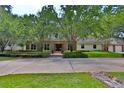Expansive home with mature trees, brick accents, and a circular driveway offering ample parking at 1300 Sw 43Rd Pl, Ocala, FL 34471