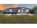 Charming blue single-story home with manicured landscaping, decorative rock, and an inviting entrance at sunset at 13115 Sw 49Th Ave, Ocala, FL 34473