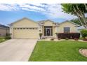Charming yellow single-story home with a well-manicured lawn and attached two car garage at 1690 Sw 158Th Ln, Ocala, FL 34473