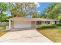 View of the home's garage, driveway and front yard with mature tree at 2220 Ne 41St St, Ocala, FL 34479