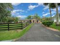 View of the front of the house with a beautiful yard, long driveway, and a black wooden fence at 530 Sw 35Th St, Ocala, FL 34471