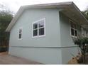 Side view of the home with a neutral color scheme, and several windows at 5949 Se 164Th Ct, Ocklawaha, FL 32179