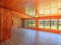 Spacious living room featuring wood-paneled walls, laminate flooring, and large windows offering views of the yard at 834 Ne 10Th Ave, Ocala, FL 34470