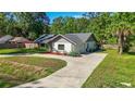 Well-manicured lawn surrounds home with stone facade, gray roof, and spacious driveway at 2406 Se 40Th Street Rd, Ocala, FL 34480