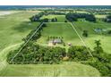Sprawling acreage showcases a ranch-style home amidst green fields, mature trees and clearly defined property lines at 2540 Ne 120Th St, Anthony, FL 32617
