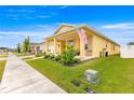 Bright yellow home featuring an inviting front porch, pristine landscaping, and an American flag waving proudly at 7641 Sw 63Rd Lane Road, Ocala, FL 34474