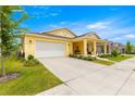 Attractive yellow home with a manicured lawn, a two-car garage, and a cozy front porch at 7641 Sw 63Rd Lane Road, Ocala, FL 34474