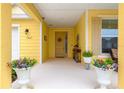 Inviting front porch featuring decorative plants and a welcoming entrance to a charming yellow home at 7641 Sw 63Rd Lane Road, Ocala, FL 34474