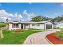 Stylish white home featuring wood shutters, a red brick driveway, and well-maintained landscaping at 8622 Baylor Cir, Orlando, FL 32817
