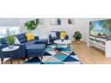 Modern living room features stylish blue seating, a patterned rug, and a large-screen TV at 8622 Baylor Cir, Orlando, FL 32817