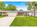 Charming home featuring a well-maintained lawn, a covered porch, and an attached garage at 8874 Sw 95Th St # E, Ocala, FL 34481