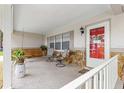 Welcoming front porch with rocking swing, chairs, stone accents, and a red front door at 8874 Sw 95Th St # E, Ocala, FL 34481
