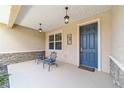 Inviting front porch with stone accents, chairs, hanging lanterns, and painted front door at 9839 Sw 90Th St, Ocala, FL 34481