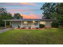 Inviting single-story home with lush green lawn and cozy front porch highlighted by a beautiful sunset at 9940 Sw 101St Pl, Ocala, FL 34481