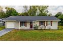 Single-story home featuring a red door, window shutters, and a well-manicured front lawn at 2140 Ne 40Th St, Ocala, FL 34479