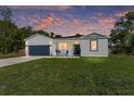 Charming single-story home featuring a well-manicured lawn and a two-car garage at dusk at 46 Fisher Lane Ter, Ocklawaha, FL 32179
