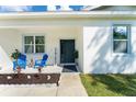 Inviting front porch with blue chairs, a 'Hey Friends' sign, and a well-kept flower bed at 46 Fisher Lane Ter, Ocklawaha, FL 32179