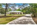 A concrete driveway leads up to this house featuring a metal roof and an attached two car garage at 505 Fisher Rd, Ocklawaha, FL 32179