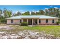 Charming single-story home featuring a light-colored metal roof and a simple, landscaped front yard at 505 Fisher Rd, Ocklawaha, FL 32179