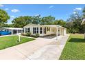 A charming single-story home featuring a lush green lawn, a carport, and an adjacent screened-in patio at 518 Saint Andrews Blvd, Lady Lake, FL 32159