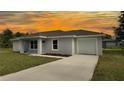 Single-story home featuring a one-car garage, concrete driveway, manicured lawn, and vibrant sunset backdrop at 5635 Nw 2Nd St, Ocala, FL 34482