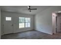 Bright living room with hardwood floors, a ceiling fan, and a large window showcasing the front yard at 5635 Nw 2Nd St, Ocala, FL 34482