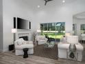 Elegant living room with fireplace, plush seating, and a serene view of the backyard at 8033 Nw 29Th Street Rd, Ocala, FL 34482