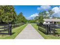 Long driveway leading to a well maintained home with lush landscaping and mature trees at 9462 Sw 72Nd Ct, Ocala, FL 34476